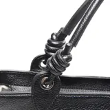 Cartera tipo tote bag color negro, con textura símil cuero y logo 'XL' en el frente. Tiene doble asa de mano y cierre superior. El interior está forrado en tela y cuenta con un bolsillo con cierre.