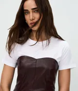 Blusa peplum sin breteles confeccionada en PU color bordó, con escote corazón y cierre posterior por cremallera. Presenta un diseño estructurado con ruedo evasé.