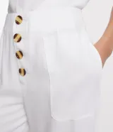 Pantalón tipo pantalona de viscosa color blanco, con cintura mediana, cierre frontal con botones y bolsillos laterales.