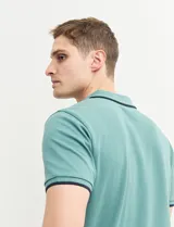Remera polo azul marino con ribetes blancos en el cuello y en los bordes de las mangas corta, y cierre frontal de botones.