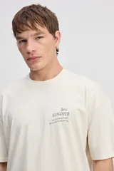 Remera boxy de algodón color beige, de silueta amplia y corta, con mangas cortas y pequeño estampado en el pecho.