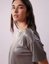 Blusa gris metalizada de tejido lurex, marca June & Hudson, con cuello redondo y ruedo con nudo en la espalda.