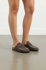 Zueco slip-on con estampado de vaca en blanco y negro, suela plana y detalle de costuras en el empeine.