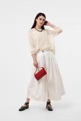 Pantalón wide leg de color blanco, de silueta amplia y gran movimiento, con pliegues delanteros que aportan volumen y estructura, y cintura definida.
