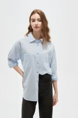 Camisa de algodón con estampado de rayas verticales finas, cuello camisero, cierre frontal con botones y bolsillos frontales tipo parche.