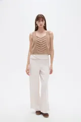 Musculosa sin mangas de color natural con cuello cuadrado y detalles de pliegues frontales en forma de chevrón.