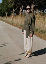 Pantalón balloon de tiro medio en color beige con estampado de rayas finas verticales oscuras. Presenta diseño abombado con bajo ajustable mediante botón.