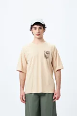 Remera color beige de corte amplio con mangas cortas y estampado de una postal con una palmera en el pecho.