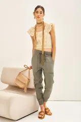Pantalón tipo babucha de gabardina elastizada, color negro, con cintura elástica ajustable mediante cordón, puños en los tobillos, bolsillos diagonales frontales y bolsillos traseros con solapa y botón.