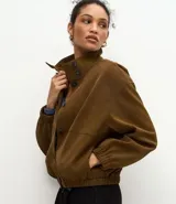 Campera de poliuretano texturizado color marrón, con cuello alto, cierre frontal con botones, mangas largas con puños elásticos y ruedo con elástico.