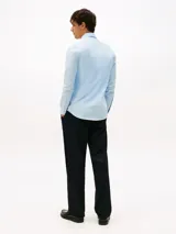 Camisa celeste de manga larga Tommy Hilfiger, confeccionada en algodón regenerativo, algodón BCI y elastano. Presenta cuello con contraste a color, cierre con botones y logo de la marca bordado en el pecho.