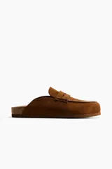 Sandalias mules tipo mocasín de gamuza color marrón, con diseño destalonado y suela de corcho y goma.