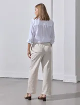 Pantalón de lino de corte recto y tiro medio, con pretina elástica ancha y lazo de ajuste frontal. Presenta bolsillos laterales verticales y bolsillos traseros.