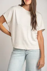 Remera oversize color crudo con sutiles rayas horizontales plateadas, mangas cortas caídas y cuello redondo.
