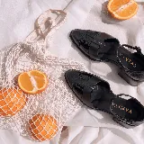 Zapato de cuero negro tipo sandalia cerrada, con taco cuadrado de madera, punta fina, tiras cruzadas y tira ajustable en el tobillo.