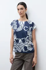Blusa de manga corta con cuello redondo, confeccionada en tela satinada con estampado abstracto en azul marino y blanco.