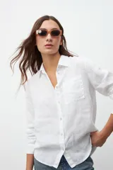 Camisa blanca de lino con cuello clásico, manga larga y bolsillo en el pecho.