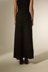 Pollera larga de corte recto y cintura elástica, confeccionada en tejido negro con textura de franjas horizontales.