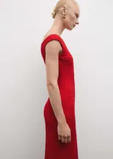 Vestido midi entallado de color rojo, con cuello barco y hombros descubiertos. Presenta un tejido con textura y abertura posterior en el bajo.