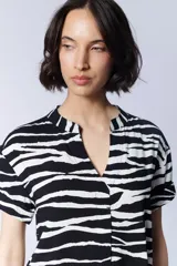 Vestido camisero corto con estampado de cebra en blanco y negro, cuello mao y mangas cortas.