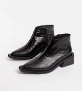 Bota corta de cuero vacuno con acabado metalizado y textura de reptil. Presenta punta fina, cierre lateral interno y taco cuadrado de madera.