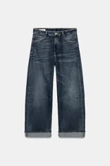 Jeans de tiro medio con corte baggy, cinco bolsillos y bajo con dobladillo. Cierre frontal con cremallera y botón metálico.