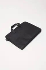 Funda para laptop de diseño minimalista en color negro, con cierre perimetral y manijas superiores para un transporte cómodo.