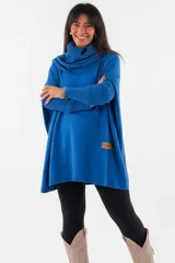 Polerón oversize de tejido de punto color naranja, con cuello alto tipo polera, mangas largas con puños acanalados y bolsillos laterales. Presenta un detalle de etiqueta de cuero en la parte inferior.