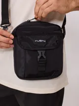 Bandolera negra de nylon con correa ajustable y logo Rusty estampado en blanco.