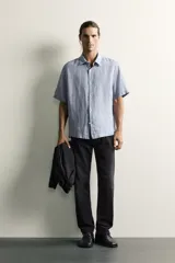 Jeans regular fit de mezclilla negra con efecto lavado, corte recto y tiro medio. Cuenta con diseño de cinco bolsillos y cierre frontal con cremallera y botón.