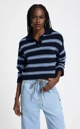 Sweater de punto con diseño a rayas horizontales en tonos azul marino y celeste. Presenta cuello polo estructurado, escote con abertura y botones, y mangas largas con puños ajustados.