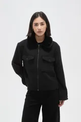 Chaqueta negra de corte holgado con cierre frontal, cuello camisero con detalle de corderito y bolsillos frontales con solapa y botones.