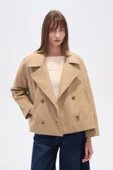 Chaqueta corta estilo peacoat, color beige, con cuello solapa y cierre cruzado de doble botonadura. Presenta un calce holgado y bolsillos laterales.