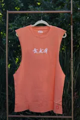 Musculosa sin mangas color naranja quemado, con cuello redondo y sisas amplias. Estampado frontal en blanco con figuras estilizadas y texto.