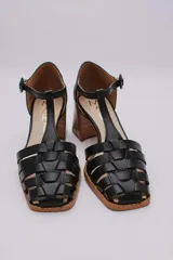 Guillerminas clásicas de cuero negro con diseño de tiras entretejidas, pulsera con hebilla y taco de madera.