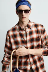 Camisa de corte regular fit confeccionada en tejido fluido de algodón y viscosa. Presenta un diseño de cuadros, cuello solapa, manga larga con puños abotonados, bolsillo en el pecho y cierre frontal con botones.