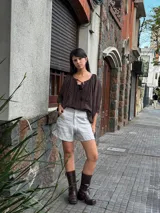 Short de lino en color celeste, con diseño de tiro alto, cierre frontal con botón a la vista y costuras decorativas verticales en el frente.