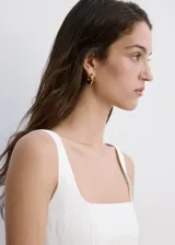 Vestido midi color blanco de lino, sin mangas, con escote cuadrado, corte en la cintura y falda evasé con bolsillos laterales.