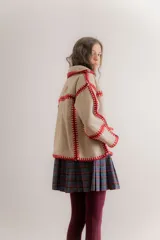 Chaqueta reversible de paño, con un lado gris oscuro con costuras decorativas en hilo rojo y el otro lado con estampado de cuadros. Presenta corte holgado, mangas largas y diseño abierto.