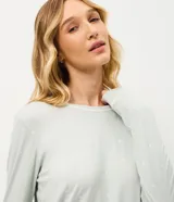 Pijama de dos piezas confeccionado en viscolycra, compuesto por una blusa de manga larga con cuello redondo y un pantalón de corte recto con cintura elástica. Presenta un estampado de lunares pequeños y detalles de vivo contrastante en los bordes.