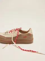 Championes urbanos de cuero en tonos tostado y marrón claro, con detalles en rojo, cordones bicolor, suela de goma y el número 1986 bordado en el talón.