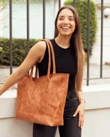 Bolso tipo shopper de cuero, color marrón tostado, con detalle de costura artesanal en el borde superior y correas largas para llevar al hombro.