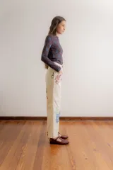 Pantalón de gabardina color crudo con estampado artístico de motivos botánicos y arquitectónicos. Presenta corte recto, tiro medio y bolsillos laterales.