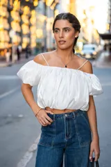 Blusa blanca con escote elástico que permite usarla con hombros descubiertos o más alta.