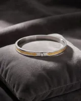 Esclava rígida de acero con baño de oro y detalle de circonia incrustada. Diseño minimalista con grabado.