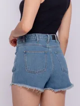 Short de jean celeste con terminación desflecada, cinco bolsillos, botón y cierre metálicos.