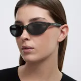 Lentes de sol con montura envolvente de diseño cat-eye en color gris traslúcido y cristales oscuros polarizados.