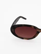 Lentes de sol con armazón ovalado de acetato en estampado carey marrón y cristales oscuros.