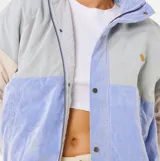 Campera de pana con diseño de bloques de color en tonos celeste, azul y beige. Presenta cuello alto, cierre frontal con cremallera y botones a presión, y puños elásticos acanalados.