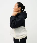 Campera cortavientos deportiva de Ashua, con diseño bicolor en negro y blanco. Presenta capucha integrada ajustable, cierre frontal con cremallera, mangas largas con puños elásticos y cintura elástica. Confeccionada en poliamida con forro de poliéster.